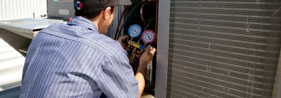 HVAC technician servicing a condenser unit in Naugatuck